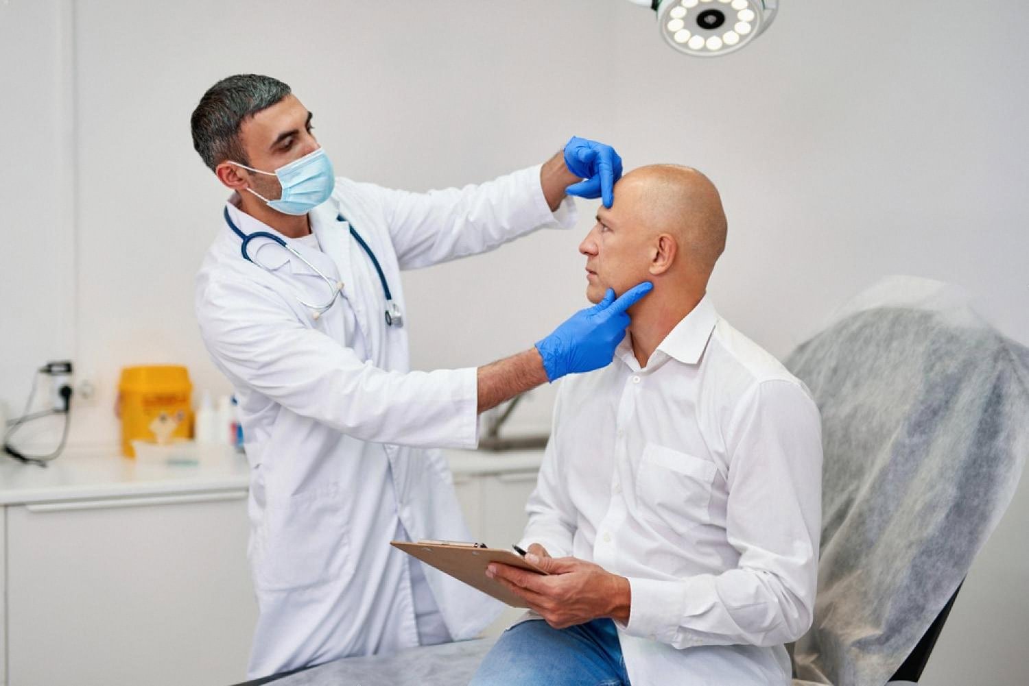 Doctor examining a male patient's scalp during a hair loss consultation